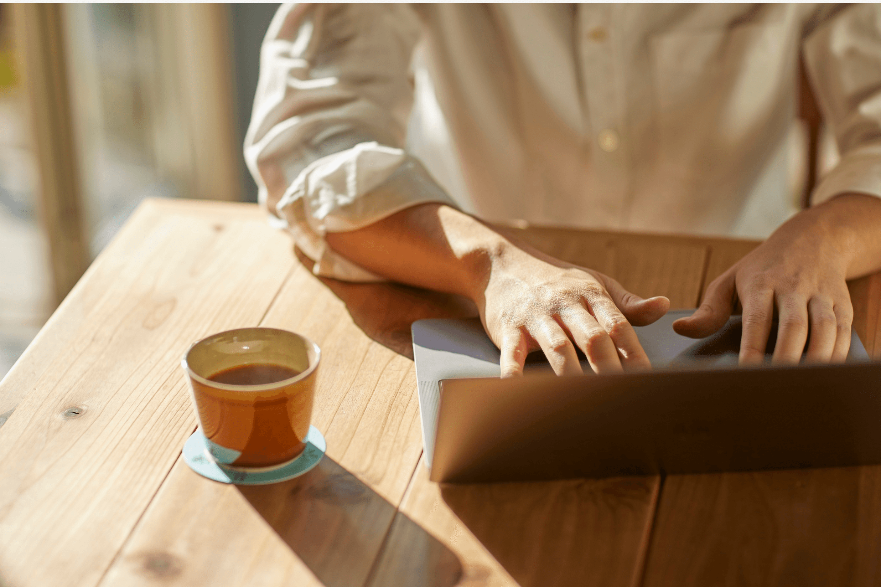 Coffee on a desk beside a laptop in golden light